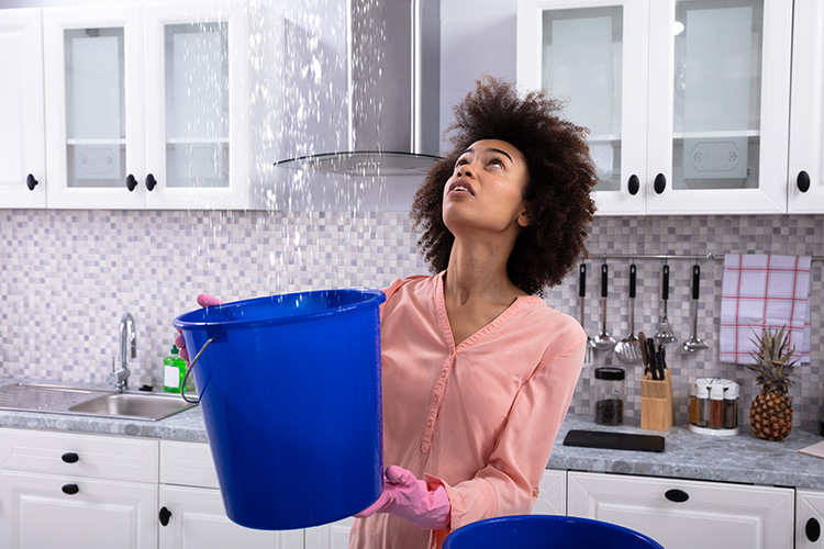 Woman holding a water bucket under a water leak.